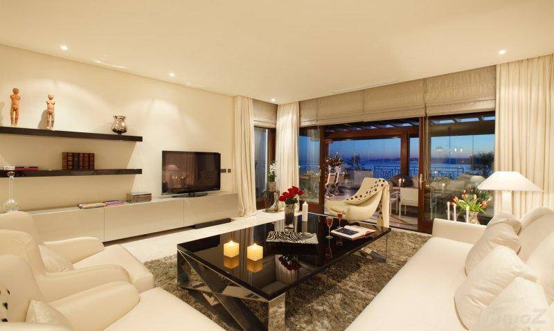 Helles Wohnzimmer mit modernen Möbeln, Teppichboden und Zugang zu einem Balkon mit Meerblick.