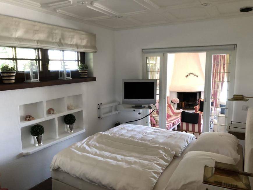 Komfortables Schlafzimmer mit Fernseher und Blick auf das angrenzende Wohnzimmer mit Kamin.