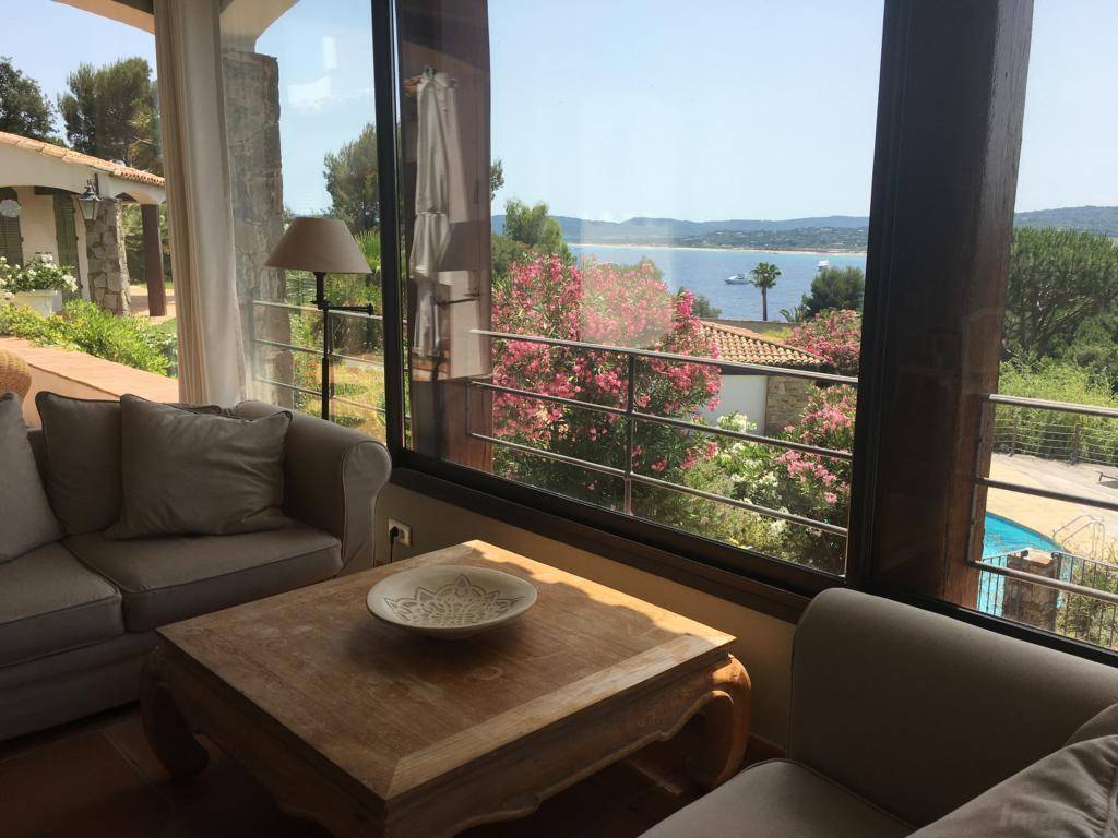 Gemütliches Wohnzimmer mit großen Fenstern, die einen weiten Blick auf das Meer und den Pool bieten.