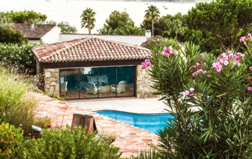Charmantes Poolhaus mit Terrakottadach und angrenzendem Pool, umgeben von mediterraner Bepflanzung.
