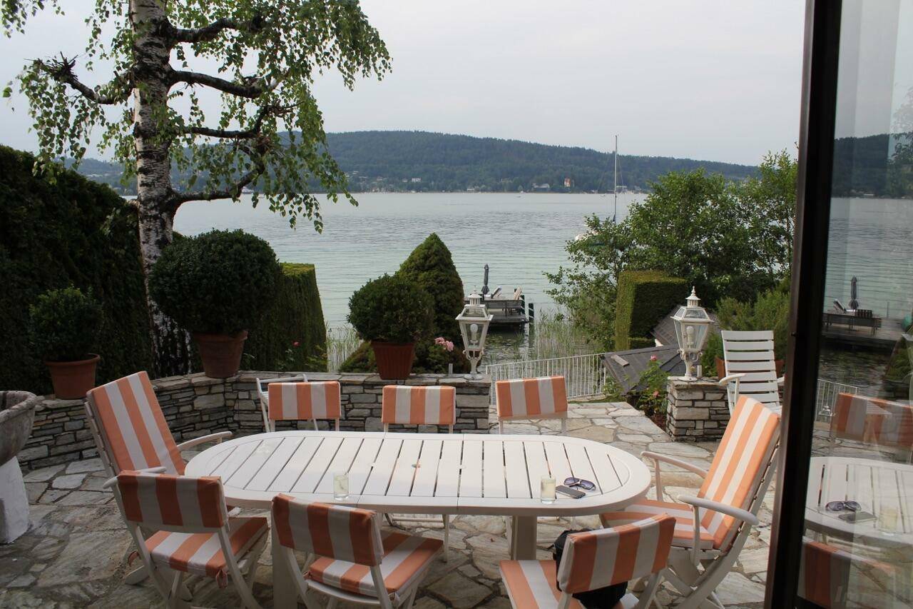 Gemütlicher Essbereich im Freien auf einer Steinterrasse mit Blick auf den ruhigen See.