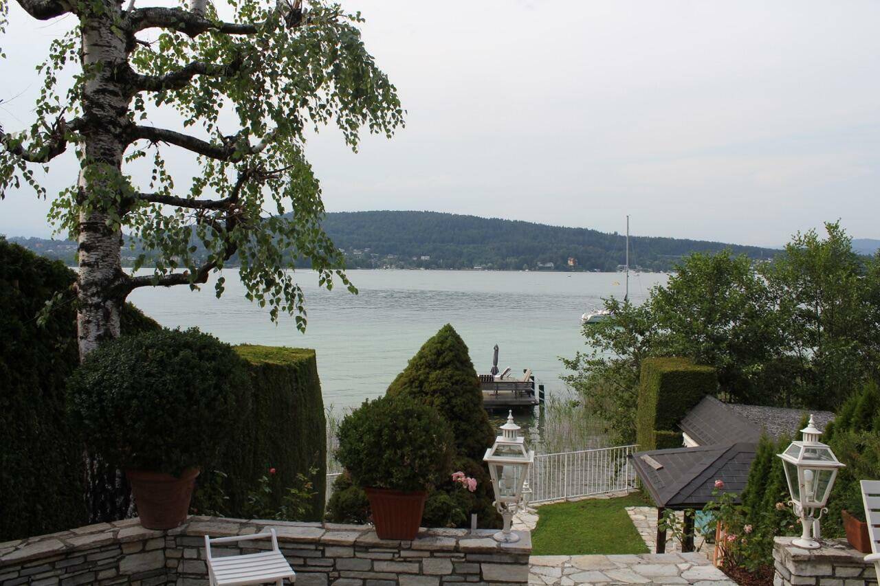 Weitläufiger Blick vom Garten auf den See, umrahmt von Bäumen und üppigem Grün.