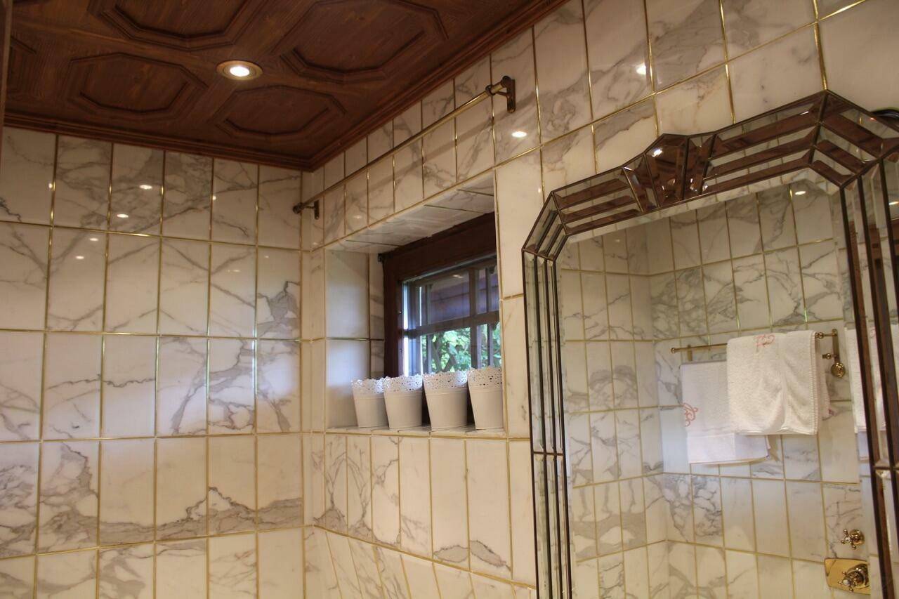 Elegantes Badezimmer mit Marmorfliesen, Holzdecke und einem Fenster für natürliches Licht.
