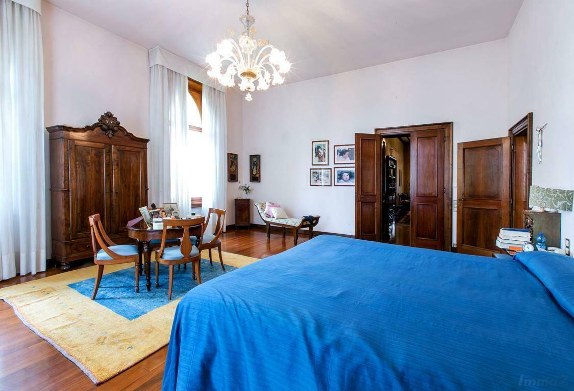 Helles Schlafzimmer mit Holzboden, einem blauen Bett und einem runden Tisch, durchflutet von natürlichem Licht.