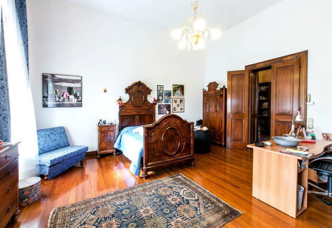 Klassisches Schlafzimmer mit Holzboden, einem antiken Holzdoppelbett und einem Schreibtisch, ideal für Ruhe und Arbeit.