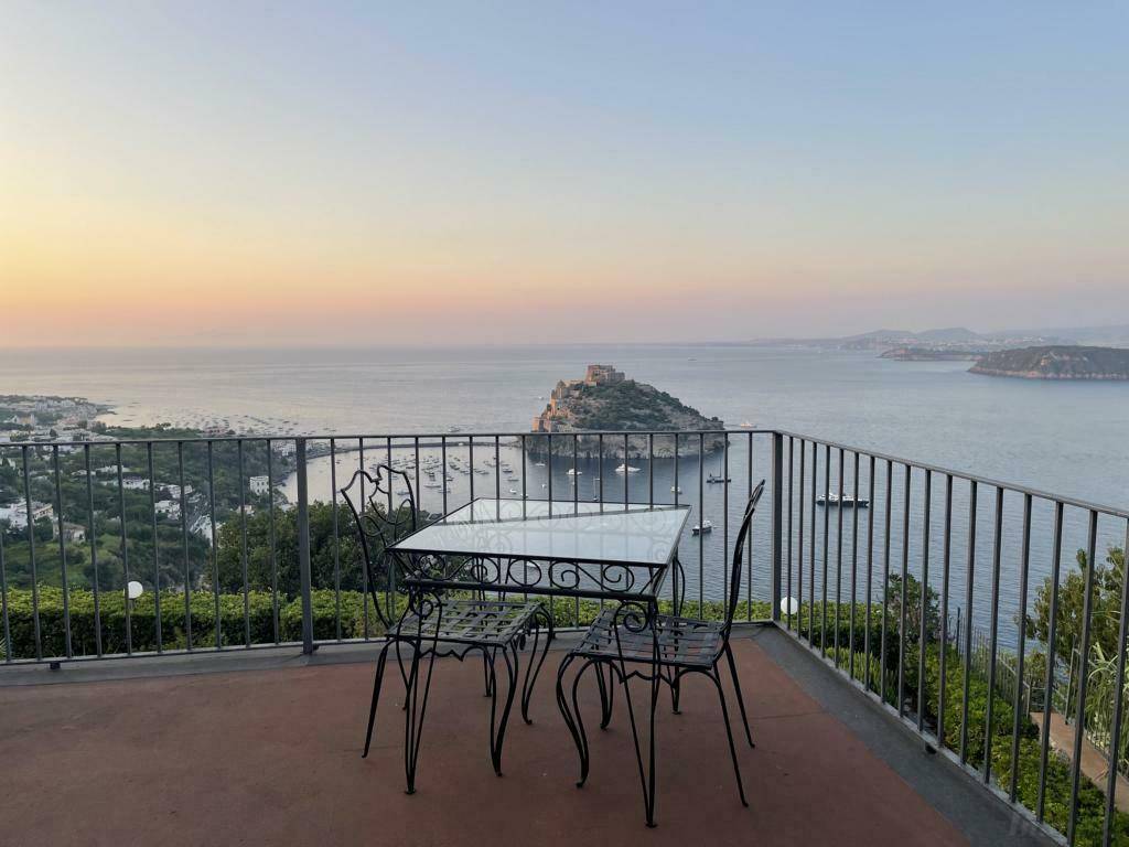Terrasse mit schmiedeeisernen Möbeln und Panoramablick auf das Meer bei Sonnenuntergang.