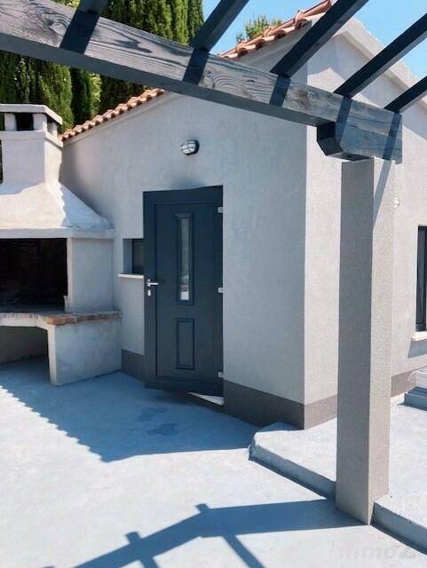 Außenbereich mit gemauertem Grill und kleiner Nebengebäude.