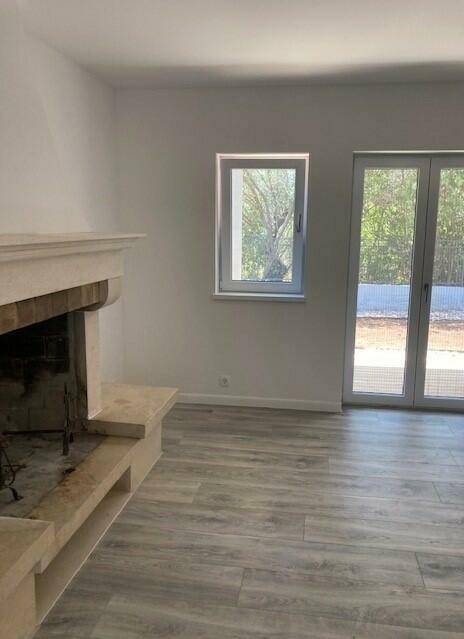 Heller Wohnraum mit Kamin, Laminatboden und Zugang zum Außenbereich.