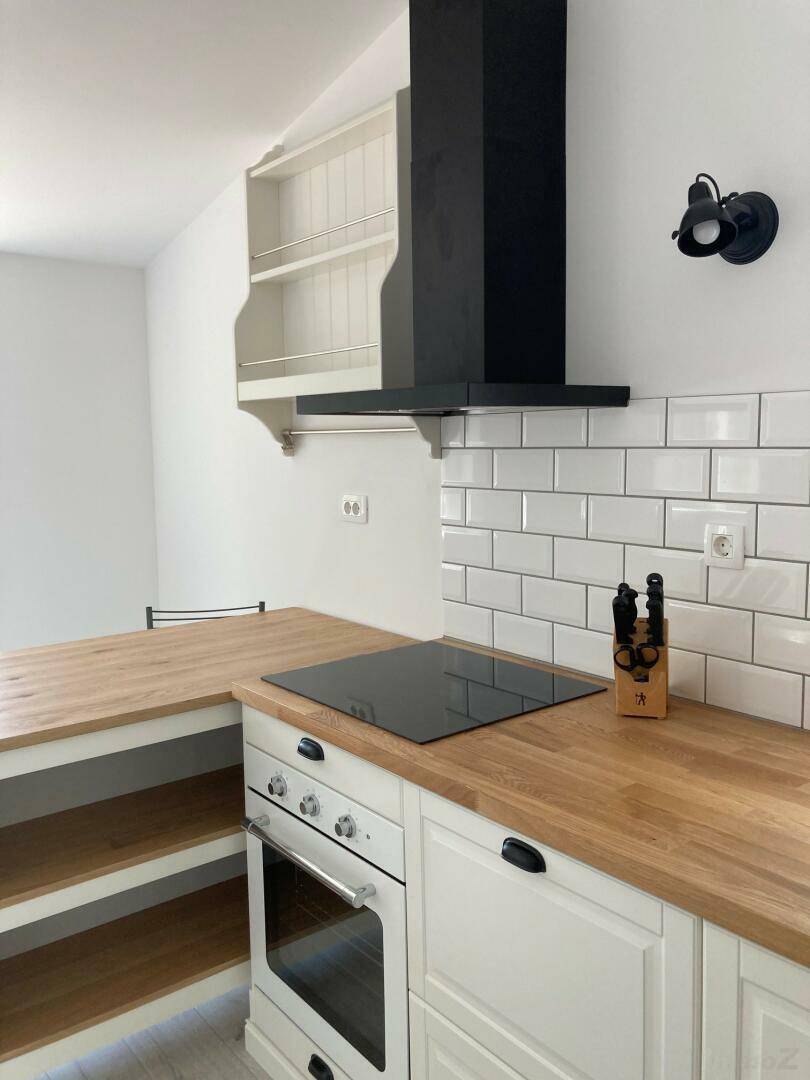 Moderne Küche mit weißen Schränken, Holz-Arbeitsplatten und Induktionskochfeld.
