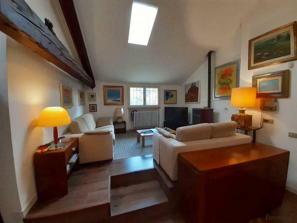 Gemütliches Wohnzimmer im Dachgeschoss mit Dachfenster, Holzbalken und moderner Einrichtung.