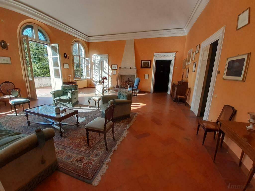 Großes Wohnzimmer mit Terrakottaboden, hohen Decken und Zugang zu einer Außenterrasse.
