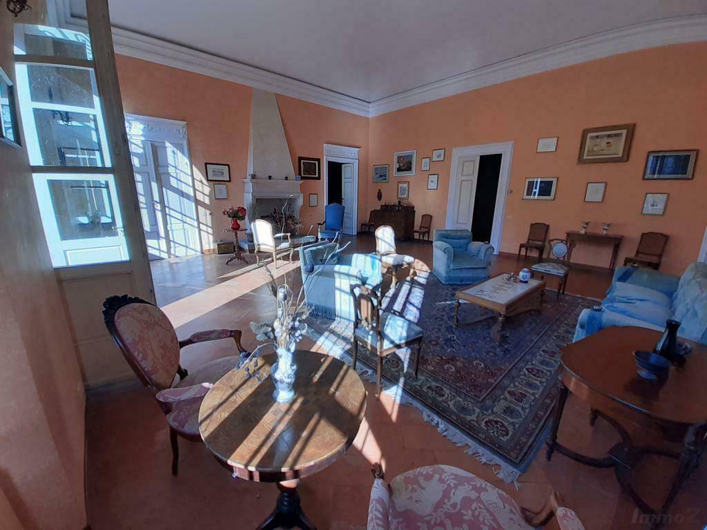 Helles Wohnzimmer mit Kamin, Terrakottaboden und traditionellen Möbeln in sonniger Atmosphäre.