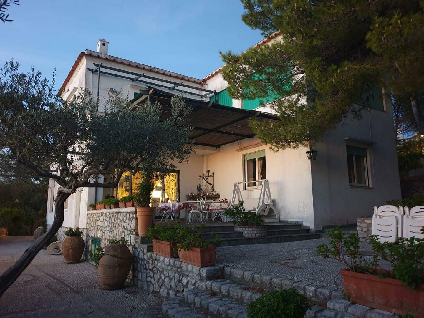 Einladende Terrasse mit Gartenmöbeln und Steinmauern am Abend, umgeben von mediterranen Pflanzen.