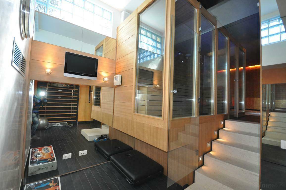 Moderner Wellnessbereich mit Sauna, Fitnessgeräten und stilvoller Beleuchtung für Entspannung.