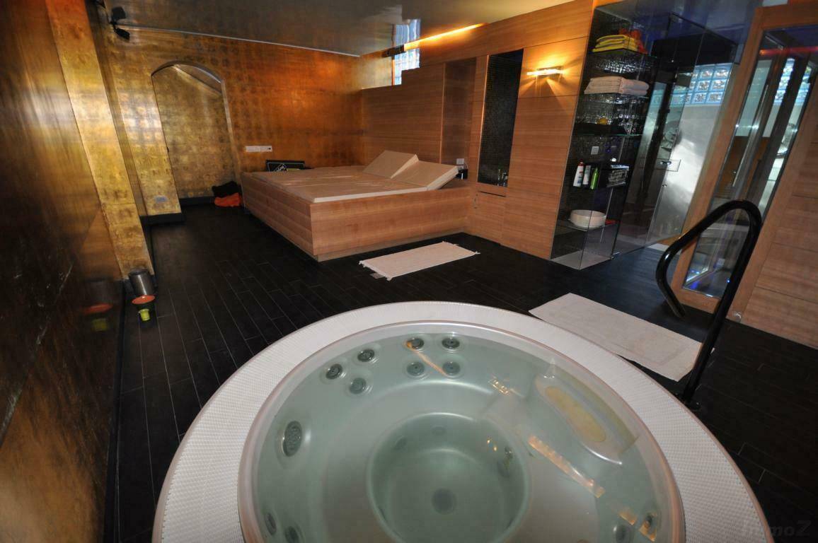 Exklusiver Wellnessbereich mit Whirlpool, Entspannungsliege und dunklem, luxuriösem Ambiente.