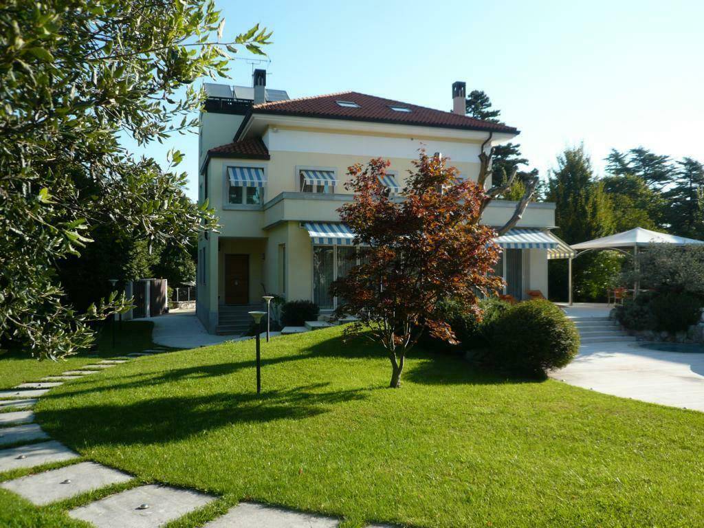 Gepflegter Vorgarten mit Rasenfläche, Bäumen und einem charmanten Haus im mediterranen Stil.