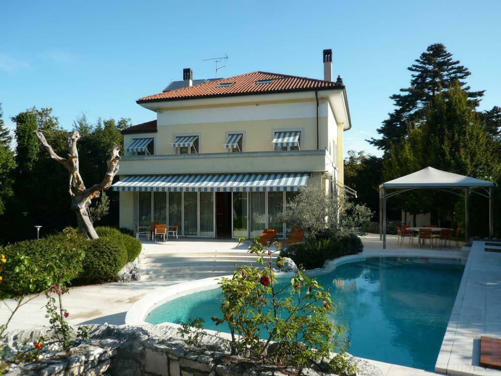 Elegantes Haus mit großem Garten, Swimmingpool und überdachtem Essbereich im Freien.