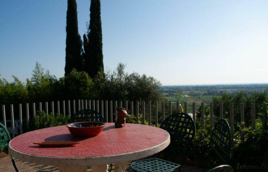 Gemütlicher Essbereich im Freien mit rotem Tisch und weitem Blick über die Landschaft.