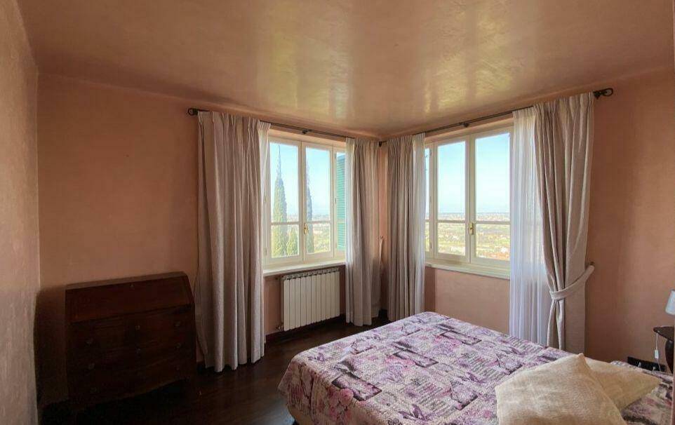 Helles Schlafzimmer mit zwei Fenstern, dunklem Boden und Blick in die Ferne.