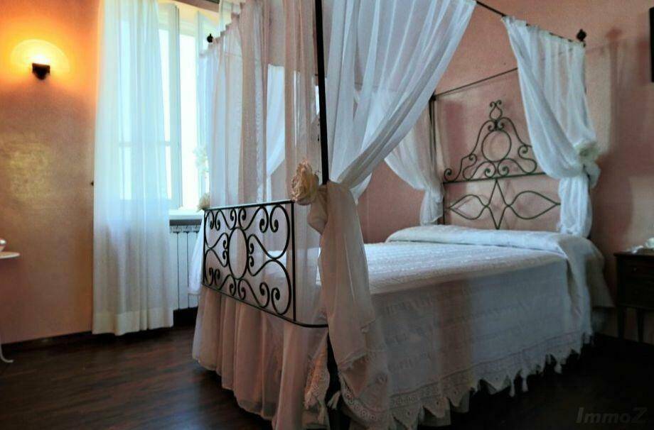 Romantisches Schlafzimmer mit Himmelbett, hellen Vorhängen und Blick nach draußen.
