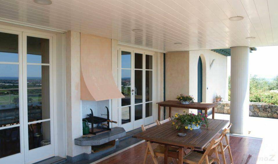Überdachte Terrasse mit Essbereich und integriertem Grill, ideal für Mahlzeiten im Freien.