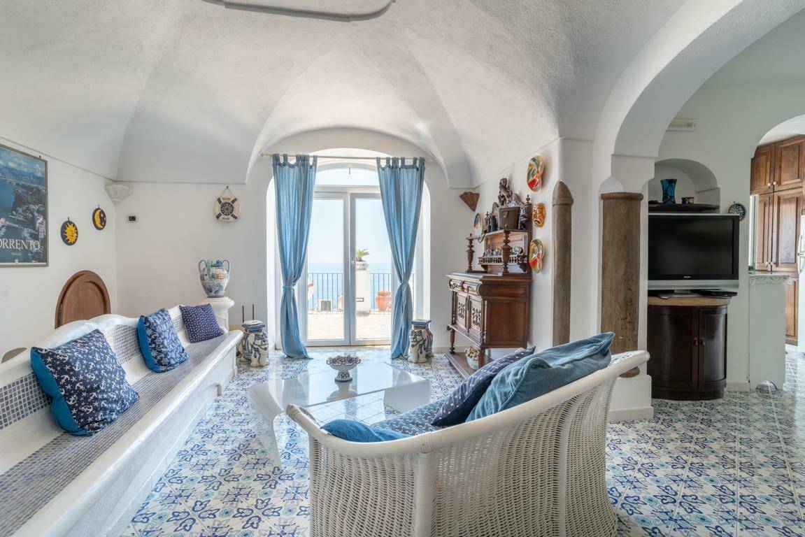 Helles Wohnzimmer mit Meerblick, Gewölbedecken und traditionellen blauen Fliesen.