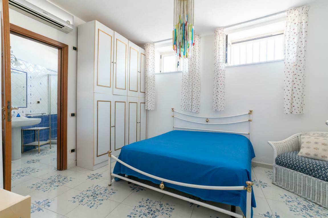 Schlafzimmer mit Doppelbett, Einbauschränken und Zugang zu einem angrenzenden Badezimmer.
