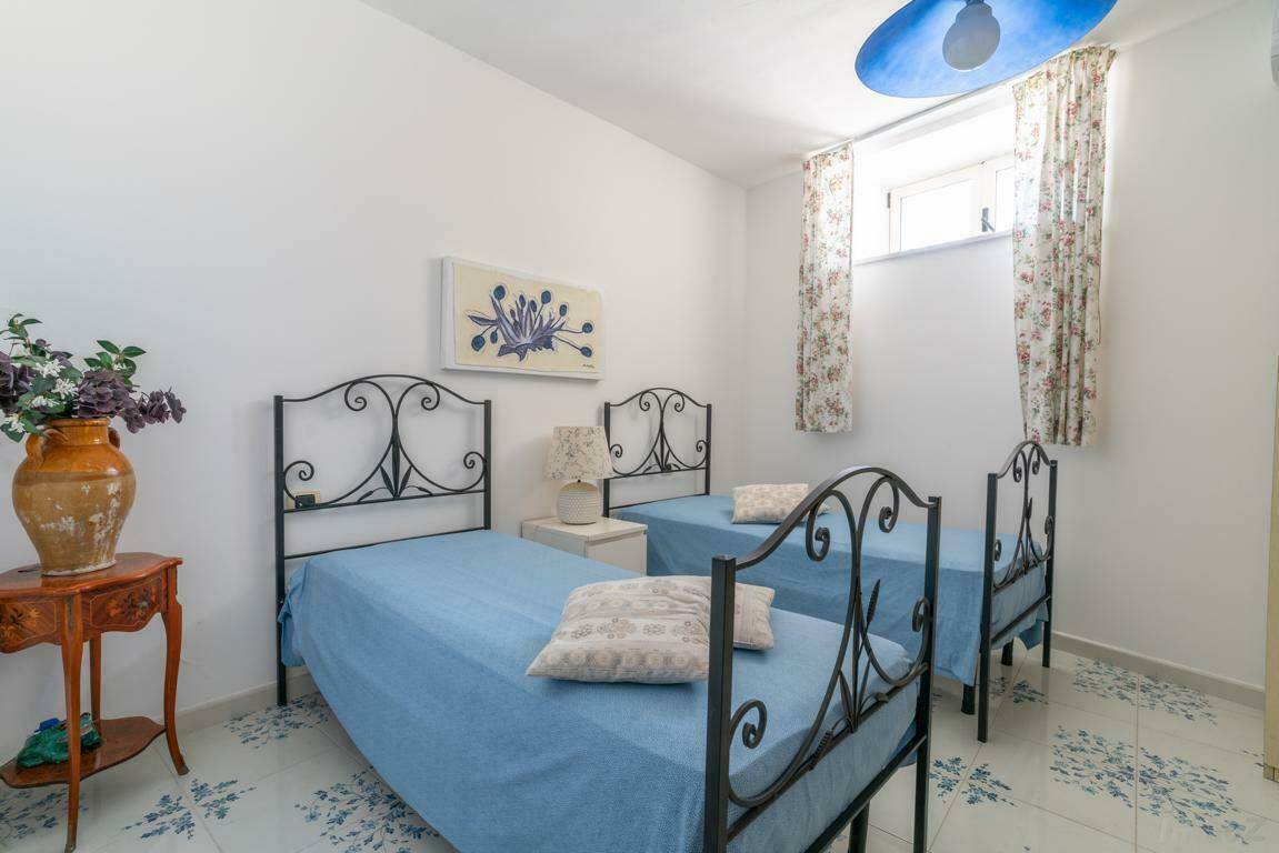 Schlafzimmer mit zwei Einzelbetten, gemusterten Fliesen und traditioneller Einrichtung.