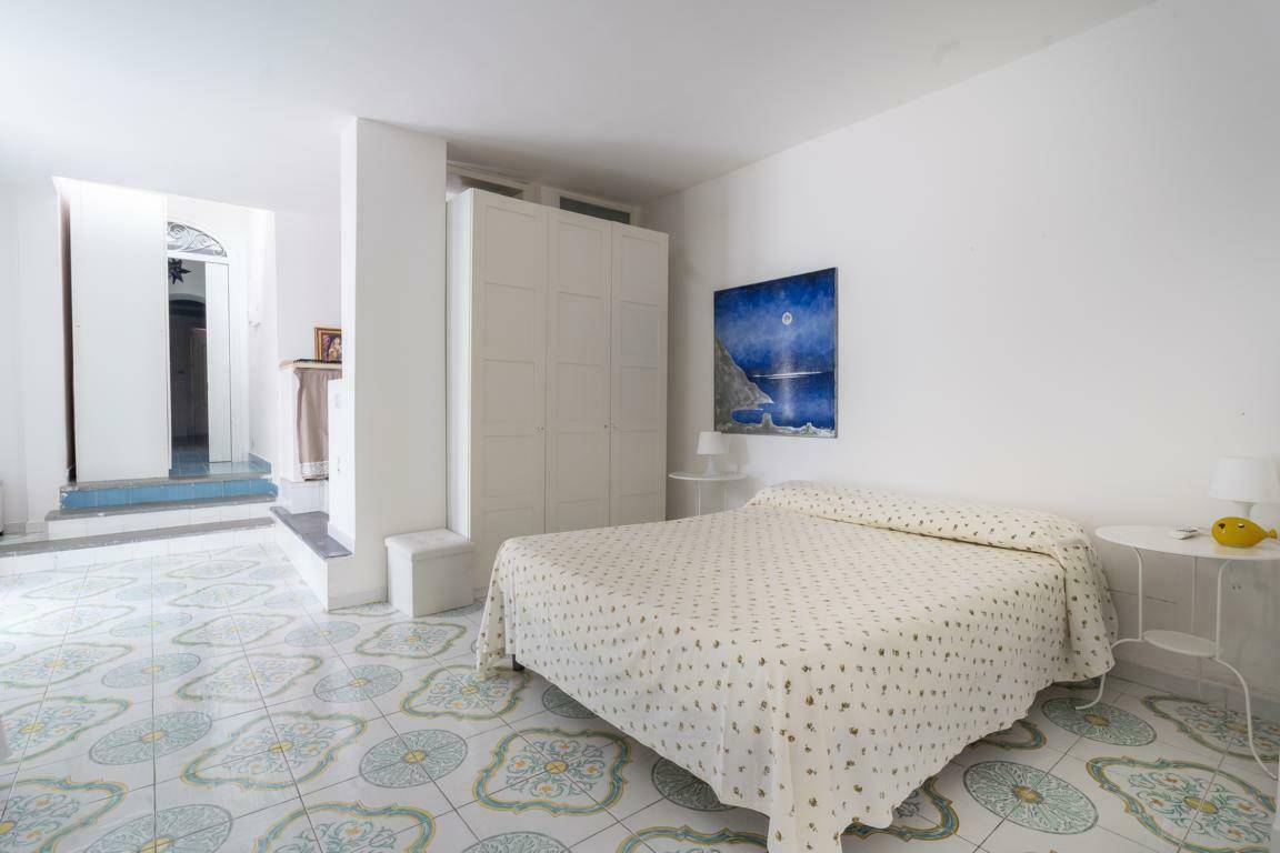Helles Schlafzimmer mit gemusterten Fliesen, weißer Einrichtung und einem modernen Kunstwerk an der Wand.