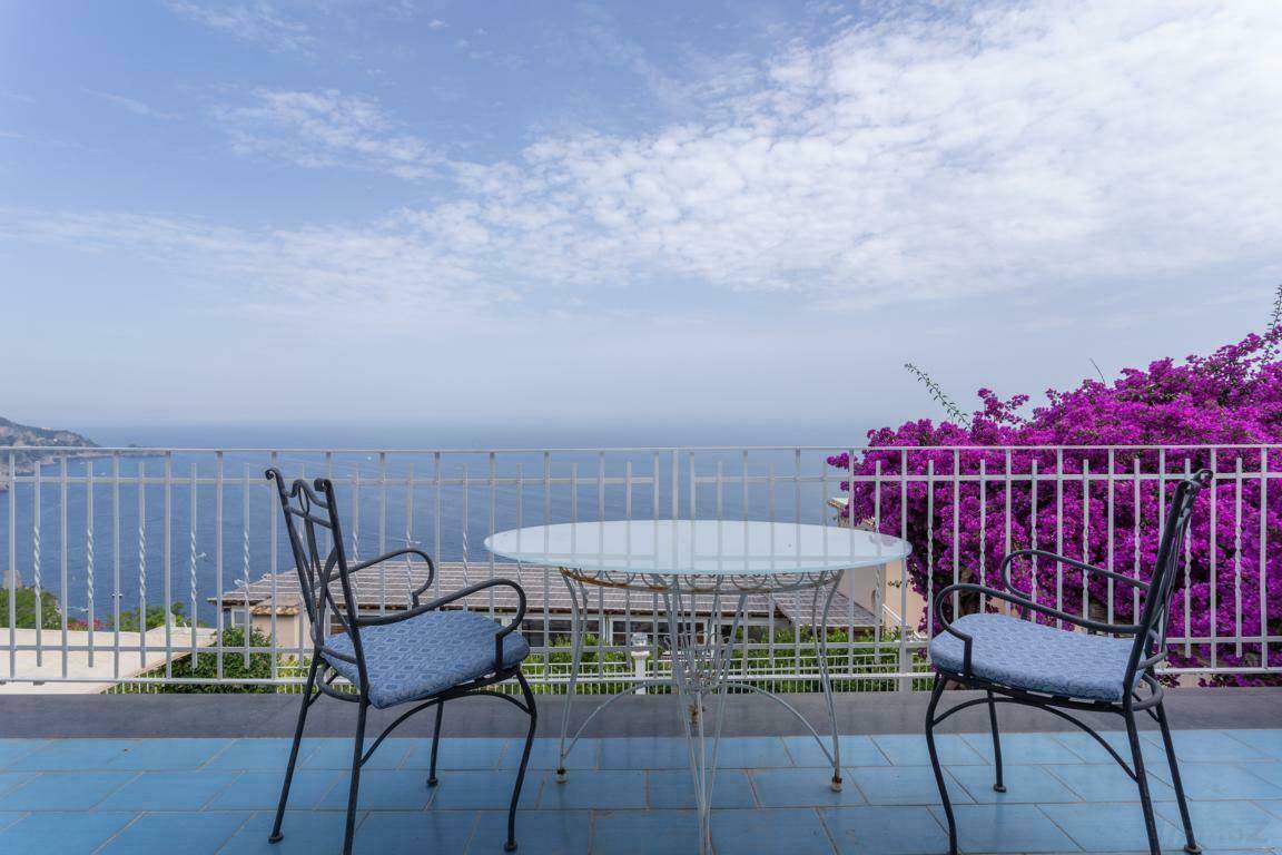 Kleiner Balkon mit Tisch und Stühlen, bietet einen atemberaubenden Blick auf das weite Meer.