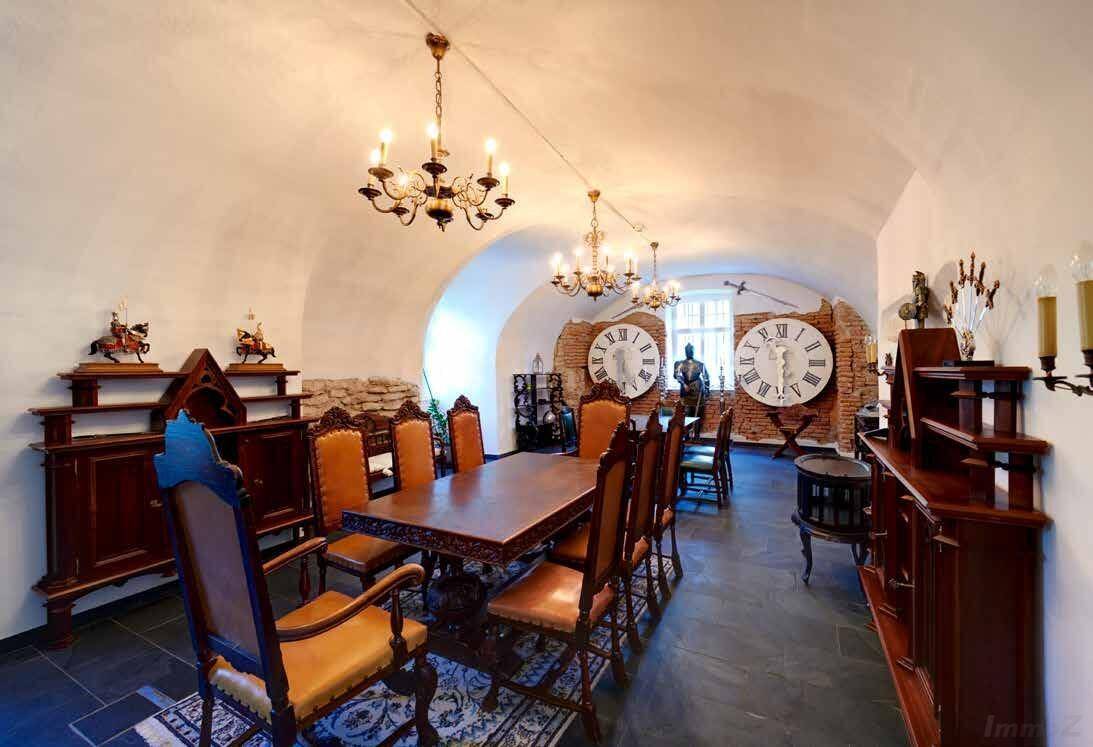 Historisches Esszimmer mit Gewölbedecke, Steinboden und großen Wanduhren als Dekoration.