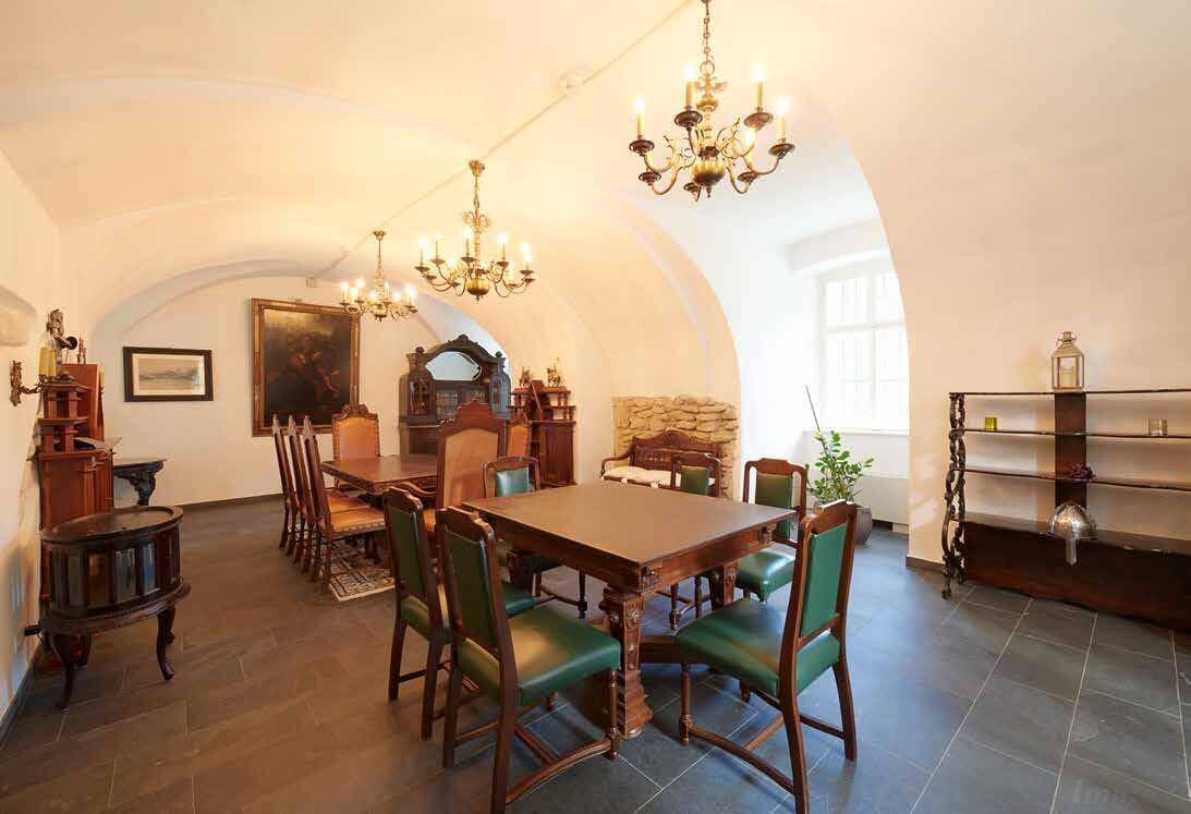 Rustikales Esszimmer mit Gewölbedecke, dunklem Steinboden und traditionellen Holzmöbeln.