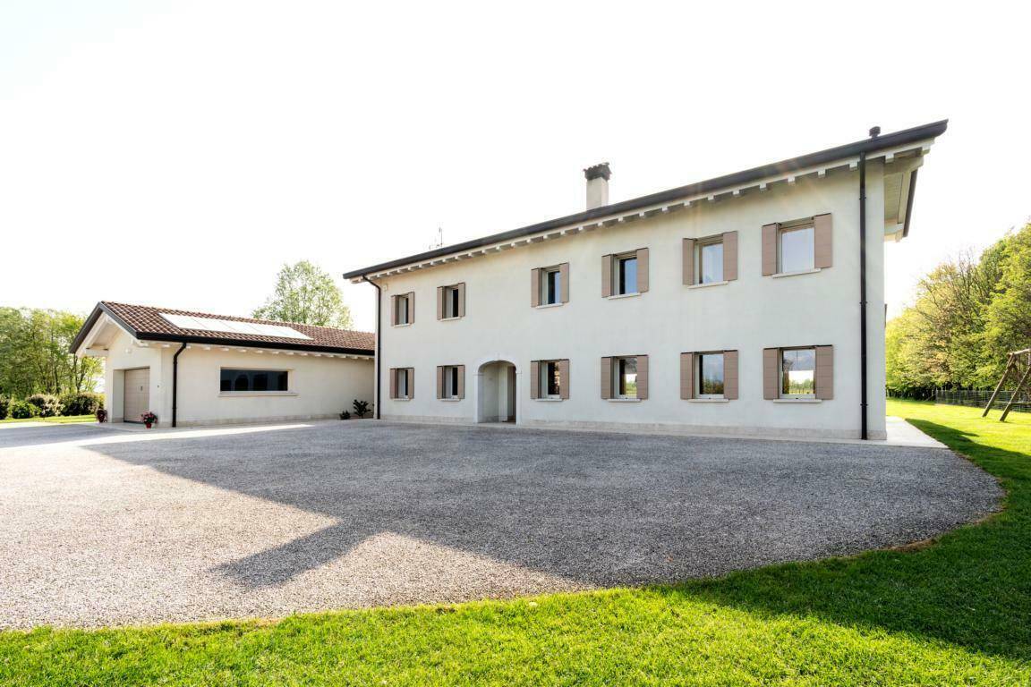 Vorderseite des modernen Hauses mit großem Kiesparkplatz und integrierter Garage.