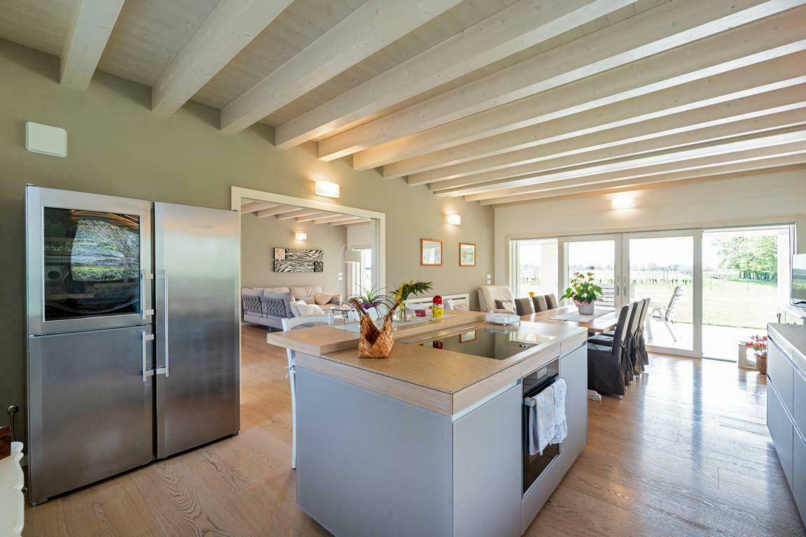 Moderne offene Küche mit Kochinsel, großem Kühlschrank und Essbereich.