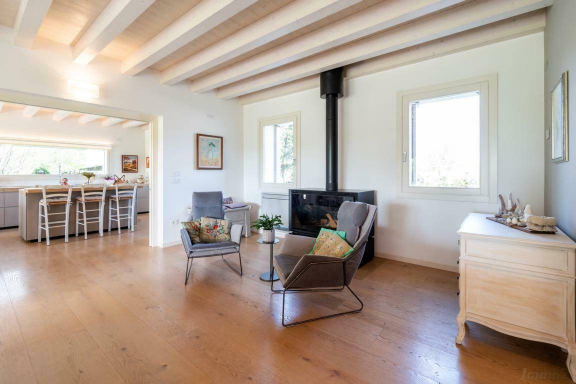 Wohnzimmer mit modernem Kamin, Holzboden und offener Verbindung zur Küche.