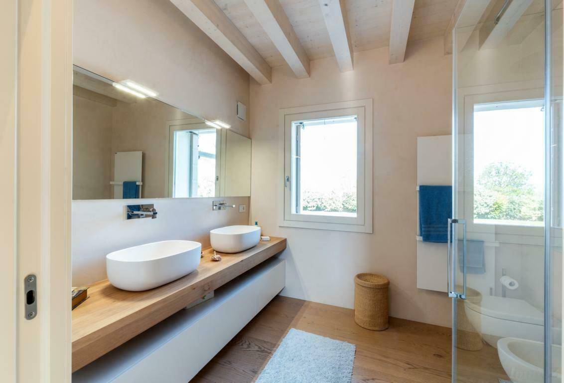 Modernes Badezimmer mit Doppelwaschbecken, begehbarer Dusche und Fenster mit Tageslicht.