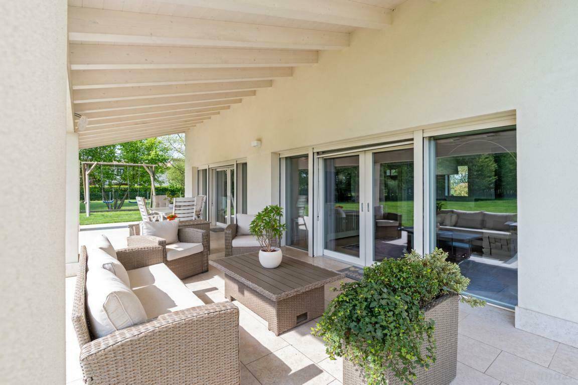Überdachte Terrasse mit bequemen Gartenmöbeln und Blick auf den weitläufigen Garten.