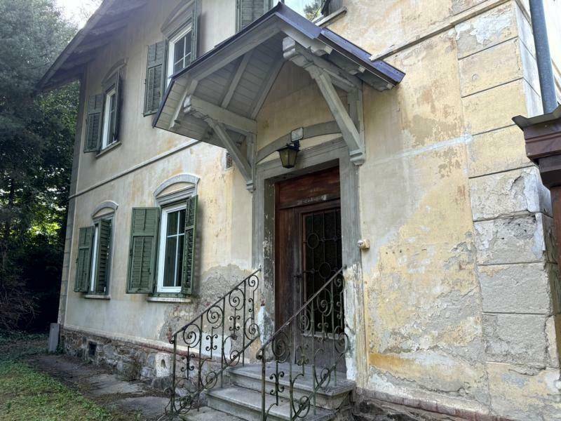 Eingangsbereich des historischen Hauses mit Vordach, schmiedeeisernem Geländer und abgenutzter Fassade.