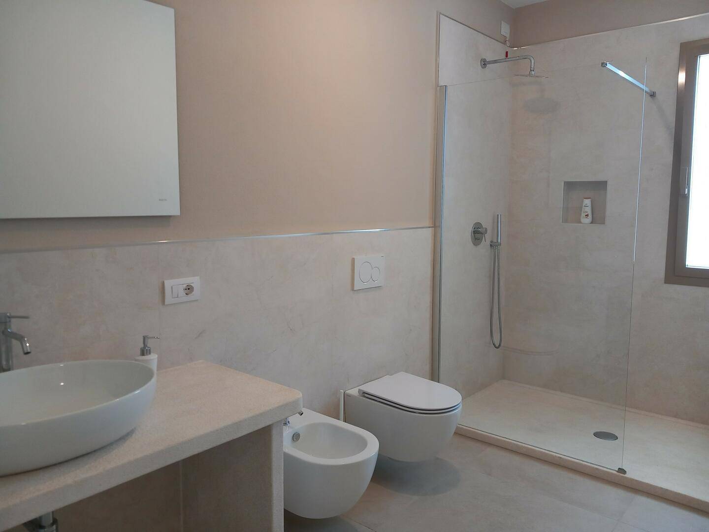 Modernes Badezimmer mit begehbarer Dusche, Bidet, wandhängendem WC und einem stilvollen Einzelwaschbecken.