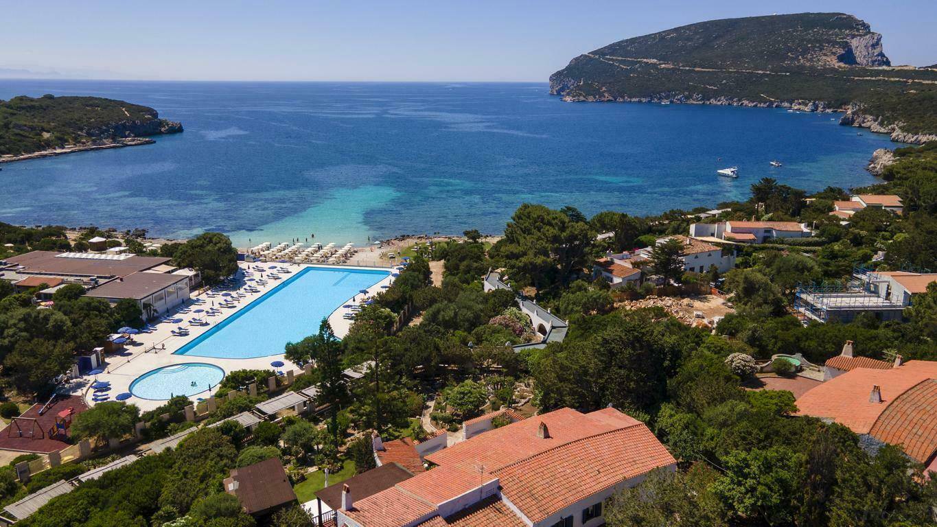 Panoramablick auf die Bucht mit kristallklarem Wasser, Sandstrand und großem Gemeinschaftspool.