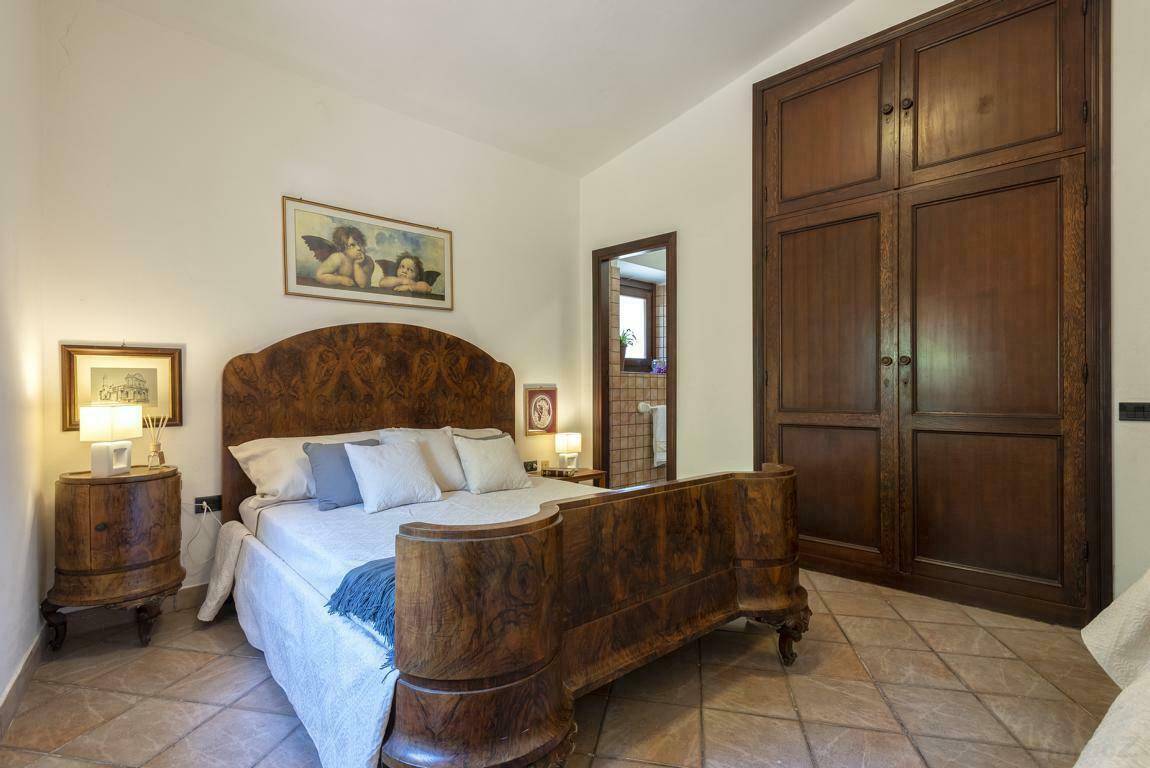 Schlafzimmer mit antik anmutendem Holzbett, passenden Nachttischen und großem Kleiderschrank.
