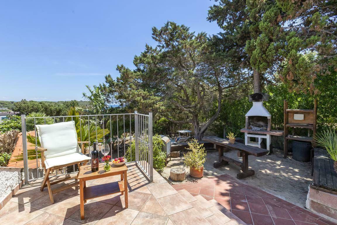 Gemütliche Terrasse mit Grillplatz, Holztisch und Sitzgelegenheiten unter schattenspendenden Bäumen.