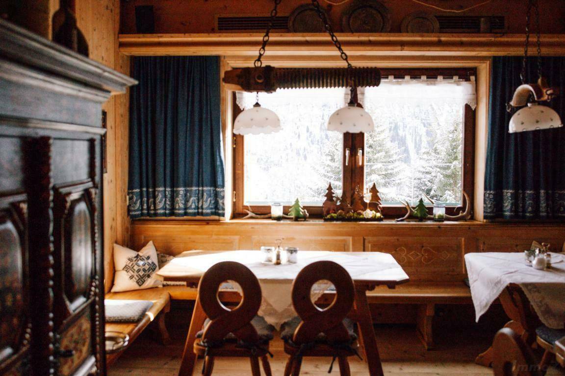 Gemütlicher Essbereich mit Holztischen und Bänken, dekoriert für die Wintersaison, mit Blick auf verschneite Bäume.
