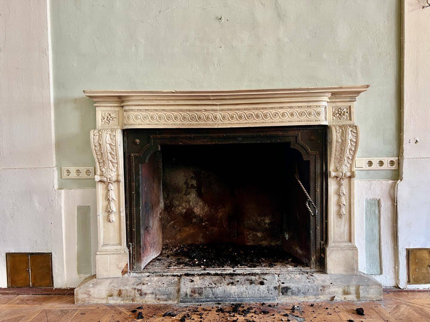 Antiker Kamin mit kunstvollen Verzierungen und Spuren der Nutzung, in einem historischen Raum.