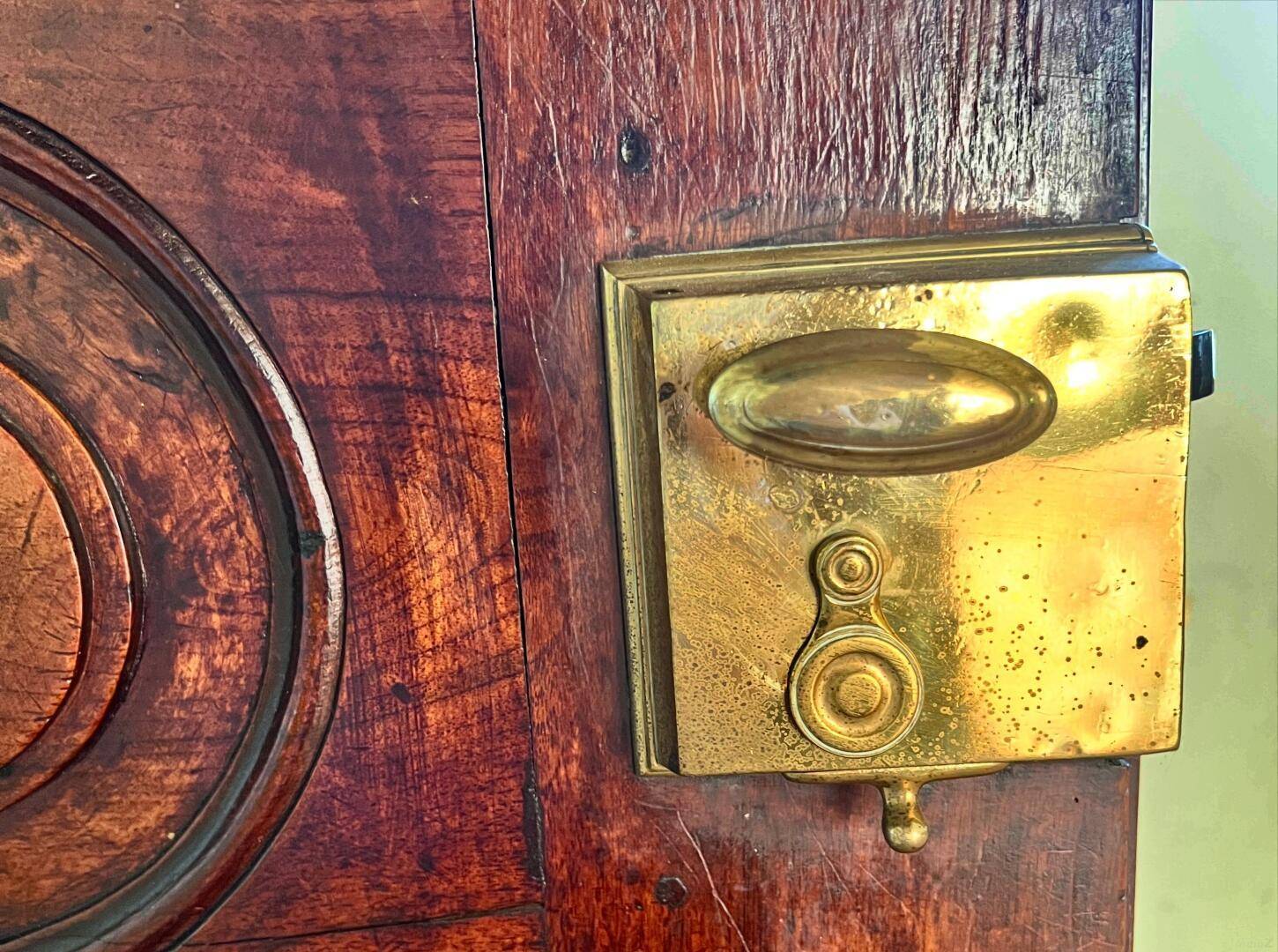 Detailaufnahme eines antiken Türschlosses aus Messing an einer Holztür.