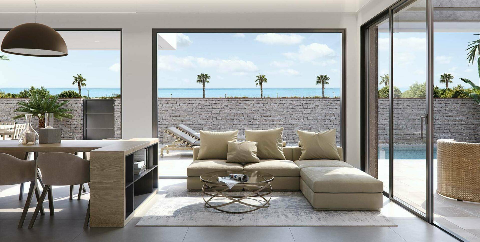 Helles Wohnzimmer mit beigem Sofa, großen Fenstern und Blick auf den Pool und das Meer.