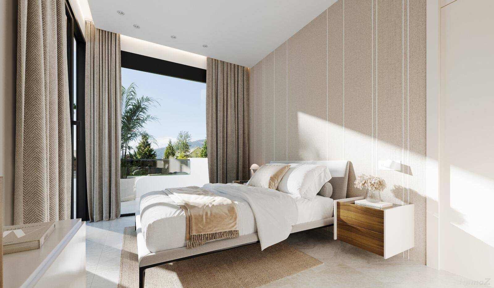 Modernes Schlafzimmer mit großem Fenster, hellem Interieur und Zugang zu einem Außenbereich.