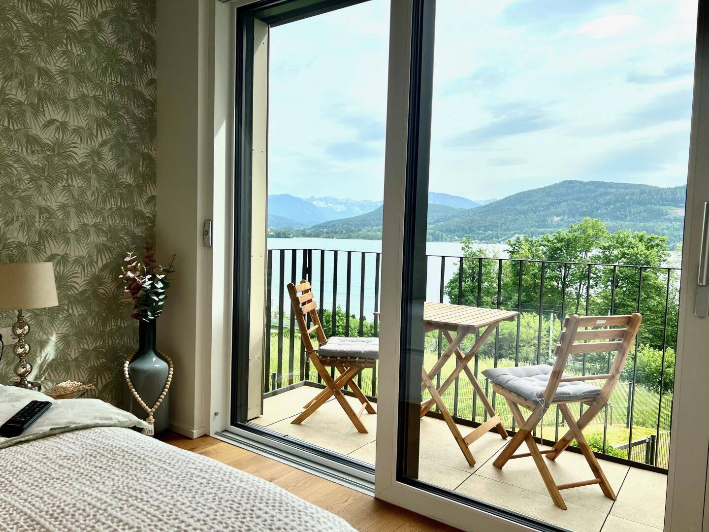 Geräumiger Balkon mit Sitzgelegenheiten und weitem Blick auf den See und die Berge.