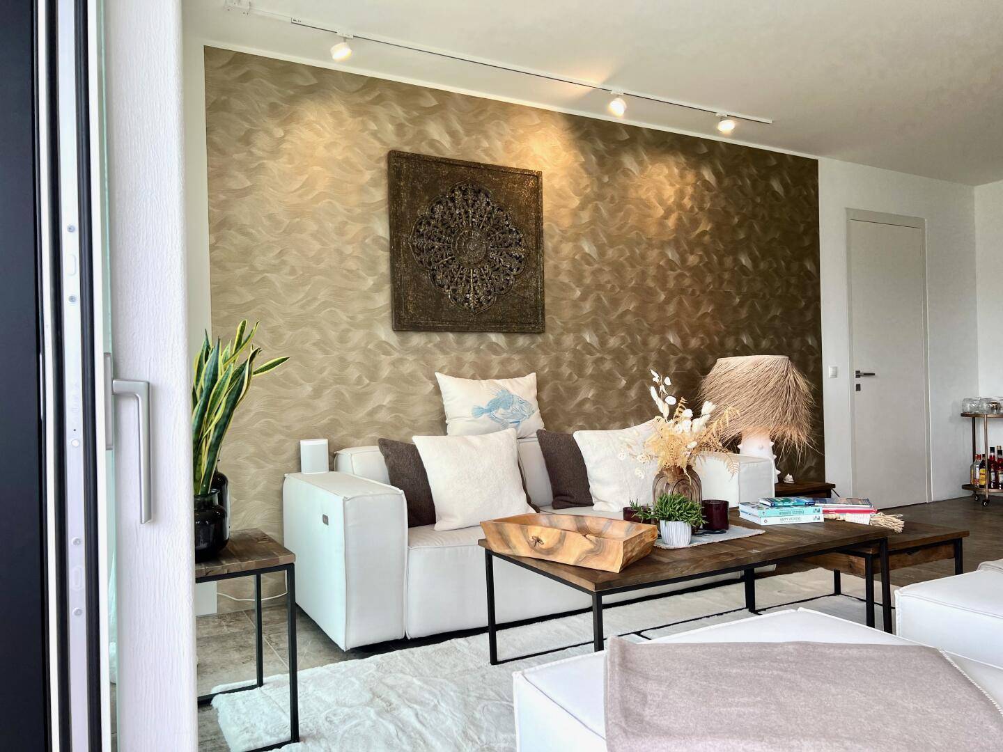 Gemütliches Wohnzimmer mit einer strukturierten Wand, modernem weißen Sofa und stilvoller Dekoration.