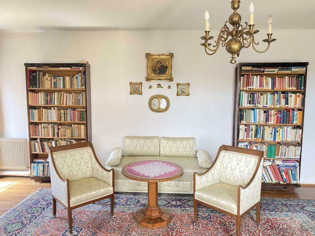 Klassisch eingerichtetes Wohnzimmer mit Bücherregalen, Sofa und zwei bequemen Sesseln.